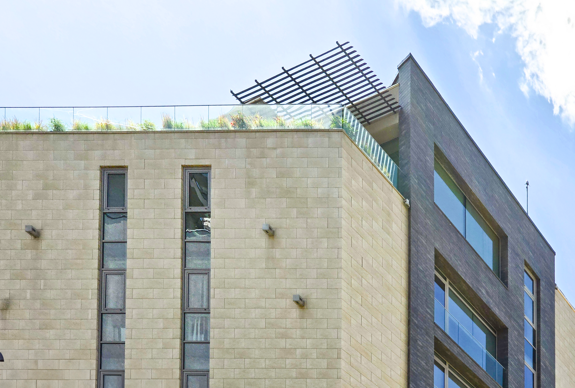 O cladire de birouri care are o terasa verde pe acoperis. Fatada ei este placata cu caramida.